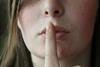 Woman holding finger to lips - non-disclosure agreement (NDA)