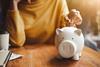 Image of a woman's hand putting a coin into a piggy bank