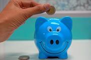 Putting coin in smiling piggy bank 