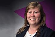 Kayleigh Brown is a white woman with shoulder-length brown hair, she's wearing a dark blazer and smiling. In the background is a dark purple triangle, pointing towards the left