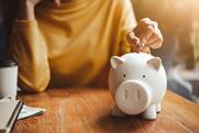 Image of a woman's hand putting a coin into a piggy bank