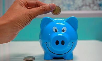 Putting coin in smiling piggy bank 