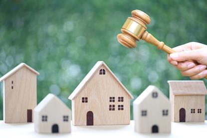 Property auction, Woman hand holding gavel wooden and model house on natural green background