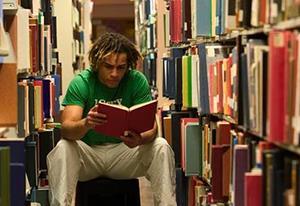 person in a library holding a book 300x206