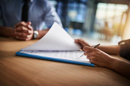 people-completing-paperwork-together-over-desk