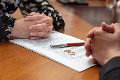 A divorcing couple sit across a table, their wedding rings sat on the divorce papers