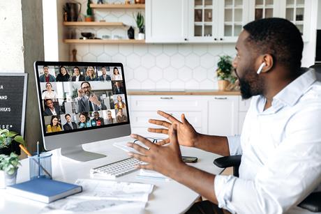 A man speaks to colleagues on a video while hybrid working from home