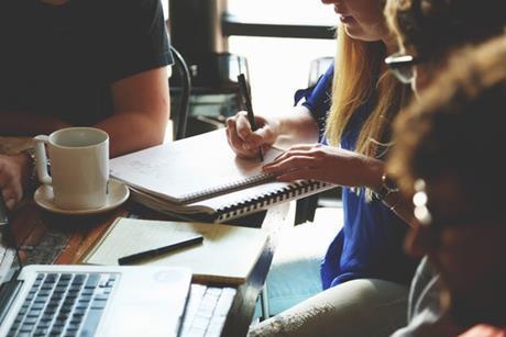 group of people sitting around table taking notes