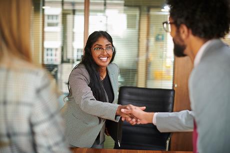 A young woman shakes hands with her interviewer