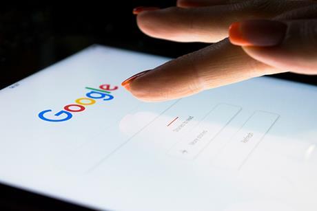 A finger hovers over the Google search bar