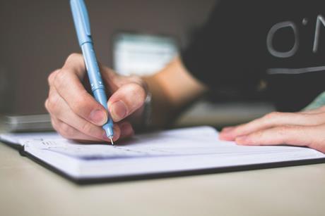 person holding pen writing on paper