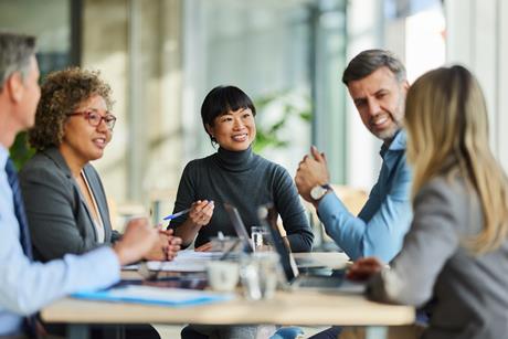 Five people sat around a meeting table