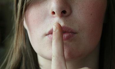 Woman holding finger to lips - non-disclosure agreement (NDA)